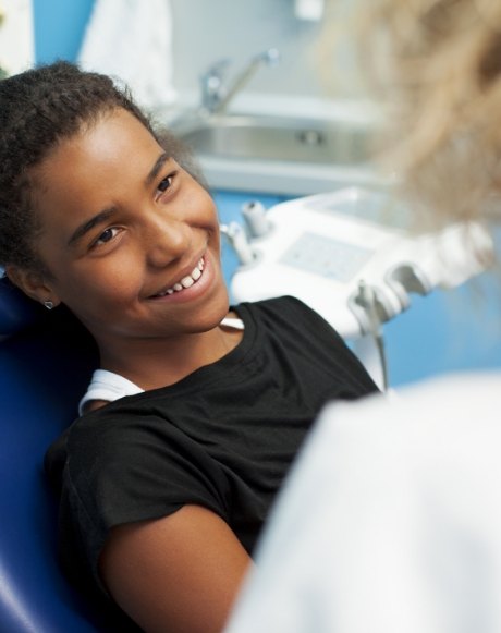 Young patient smiling at dentist during dental checkup and teeth cleaning for kids