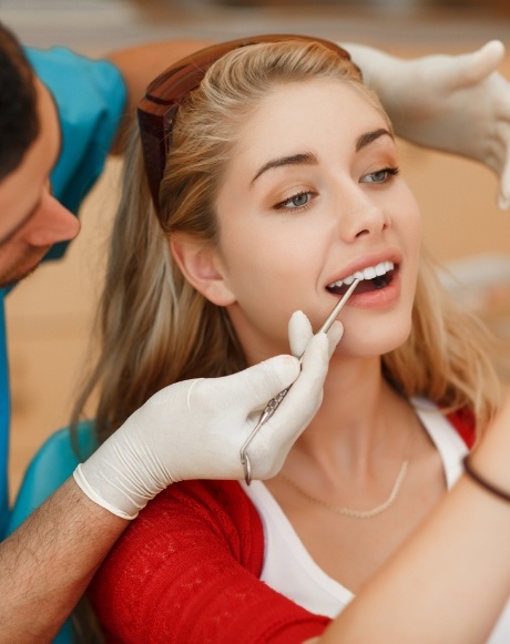 Dentist examining woman's smile after cosmetic dental bonding