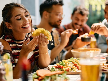 Woman smiling while eating lunch with friends at restaurant