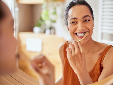 Woman smiling while brushing her teeth