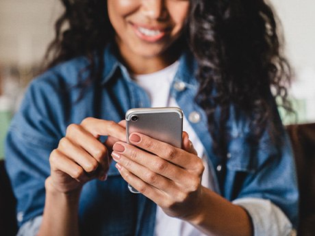 Woman smiling at phone while sitting on couch