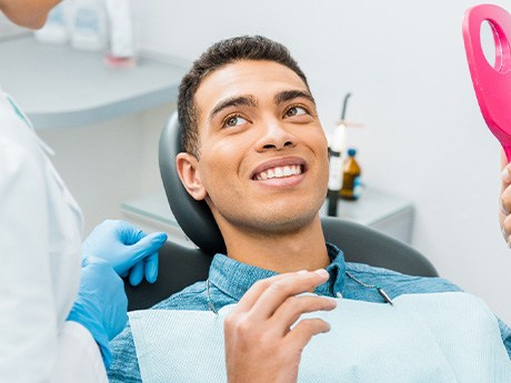 Patient smiling while holding small mirror