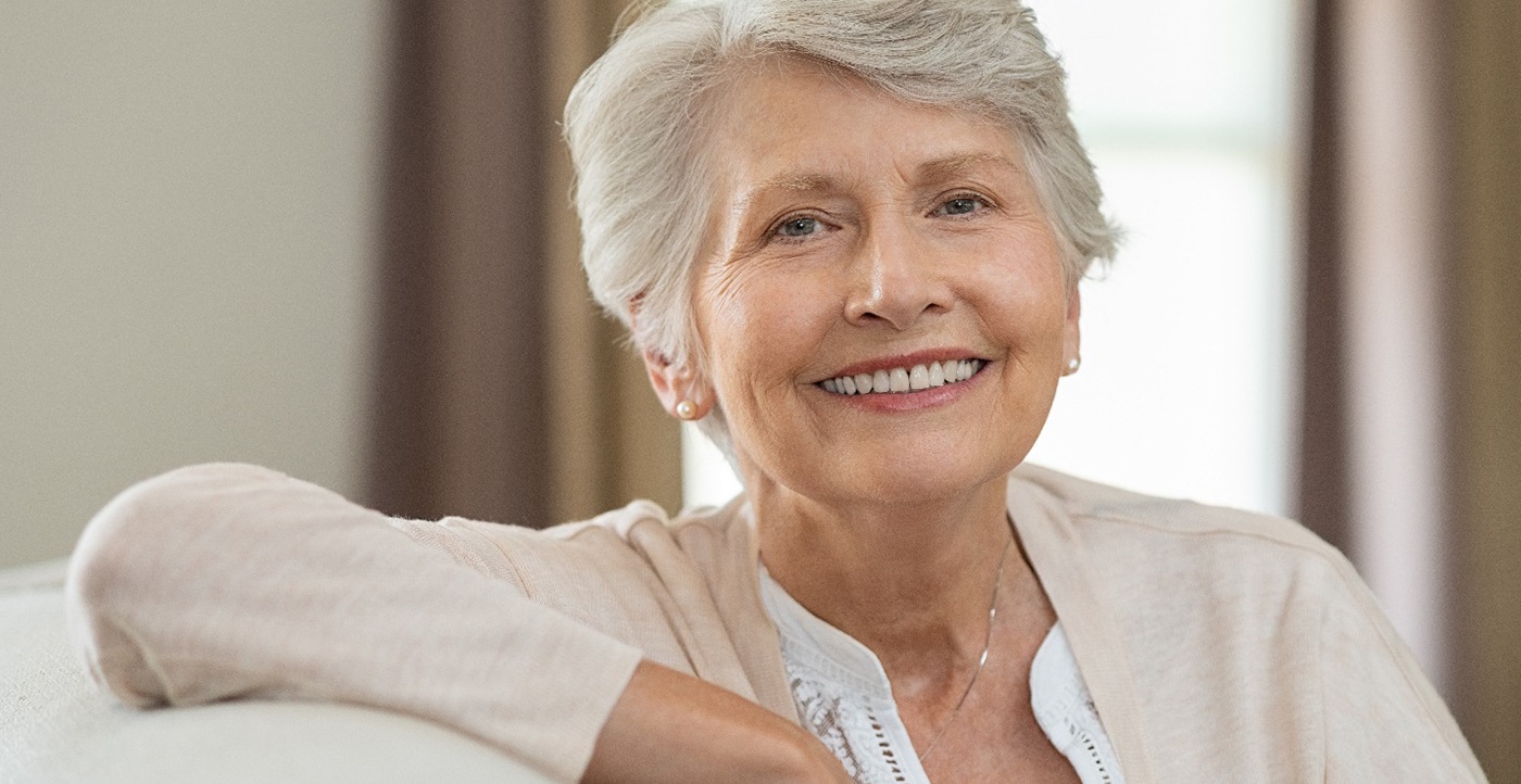 Senior woman sitting on couch resting arm on its back