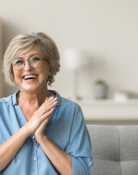 Senior woman sitting on grey couch and smiling