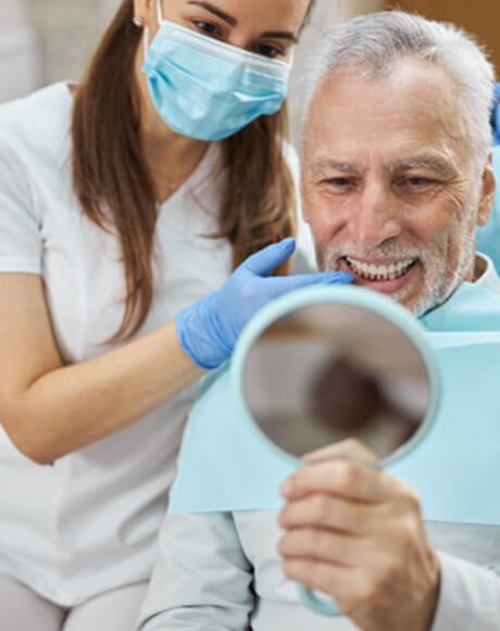 a patient checking his new dental implants with a mirror