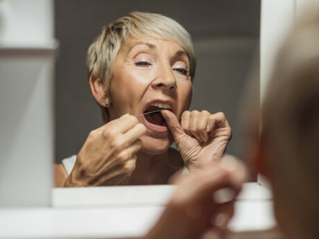 an older woman flossing her dental implants