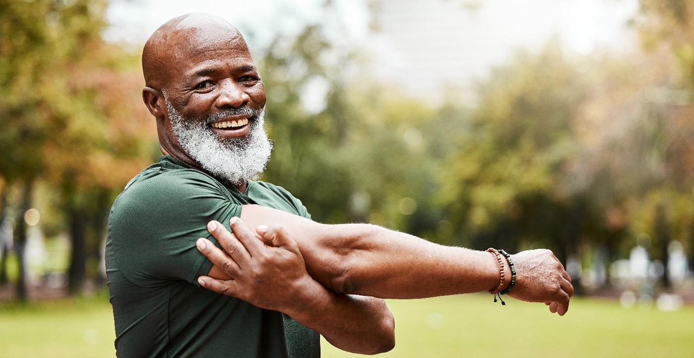 Bearded man standing outside stretching his arms