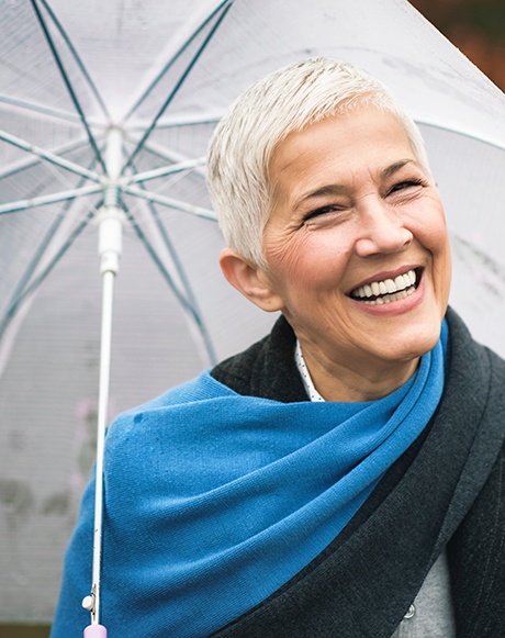 Senior woman with umbrella standing and smiling