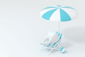 Fake tooth sitting on a tiny striped beach chair with an umbrella and ball