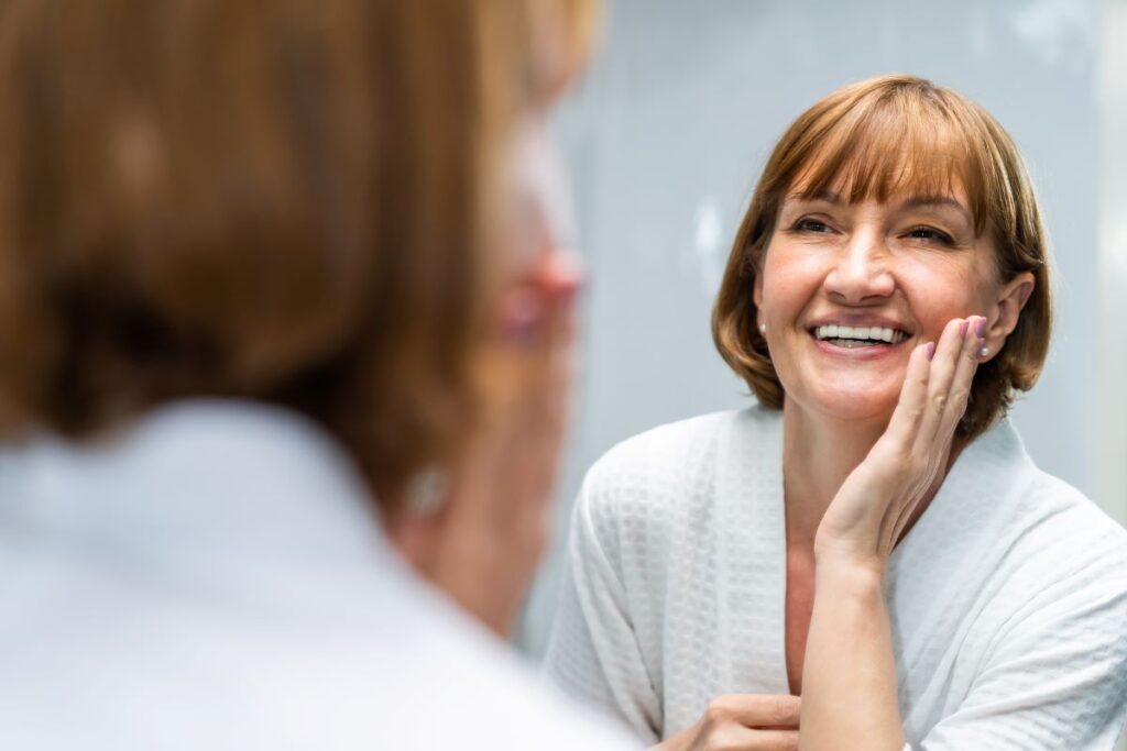 A woman looking at her face in the mirror.